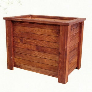 May include: A rectangular wooden planter box with a rich, reddish-brown stain. The box is constructed from horizontal planks and features a simple, clean design. The planter is suitable for outdoor or indoor use.