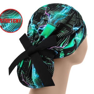 May include: A black and green patterned scrub cap with a bow. The cap features a circuit board design with neon green and blue accents. The word "STRETCHY" is in a red circle.