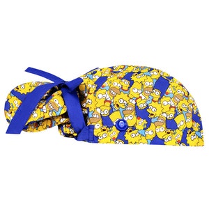 Puede incluir: Un gorro de quir&oacute;fano azul y amarillo con un patr&oacute;n de personajes de dibujos animados de Los Simpson. El gorro tiene una corbata azul y un bot&oacute;n en la parte superior.