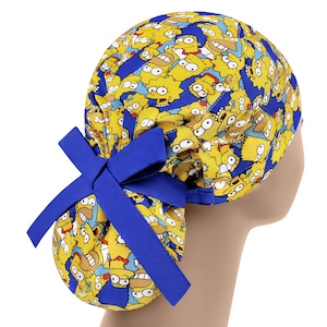 Puede incluir: Un gorro de quir&oacute;fano azul y amarillo con una corbata. El gorro presenta un patr&oacute;n repetido de personajes de dibujos animados con piel amarilla y cabello negro.