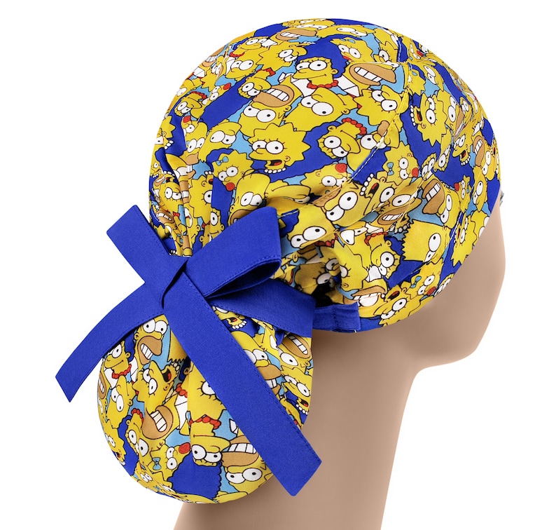 Puede incluir: Un gorro de quir&oacute;fano azul y amarillo con una corbata. El gorro presenta un patr&oacute;n repetido de personajes de dibujos animados con piel amarilla y cabello negro.