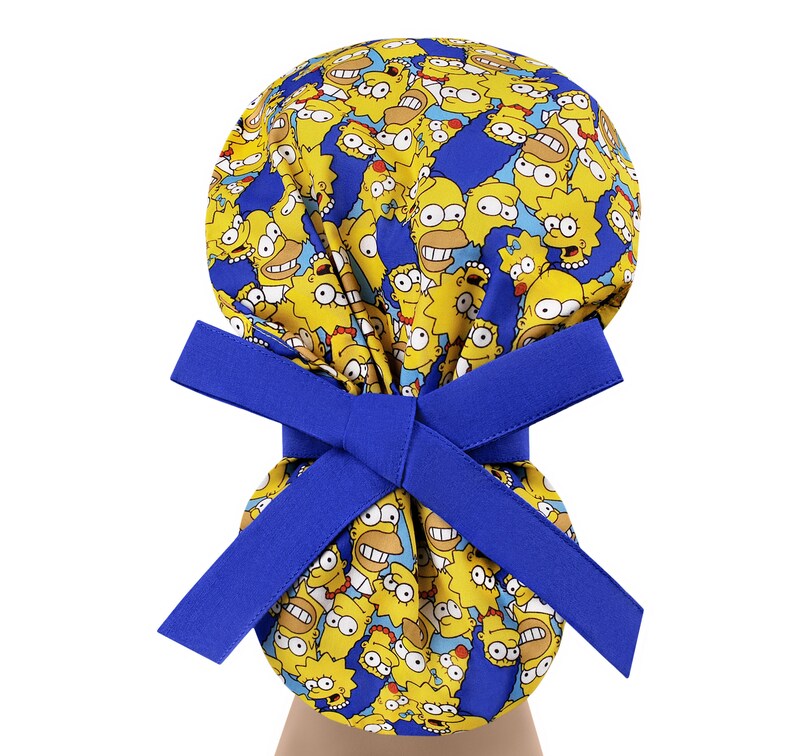 Puede incluir: Un gorro de quir&oacute;fano azul con un patr&oacute;n amarillo y azul de personajes de dibujos animados. El gorro tiene una cinta azul.