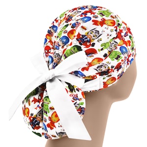 May include: A white scrub cap featuring a colorful pattern of comic book superheroes, including Captain America, Iron Man, and Thor. The cap has a white bow at the back. The cap is designed for medical professionals.