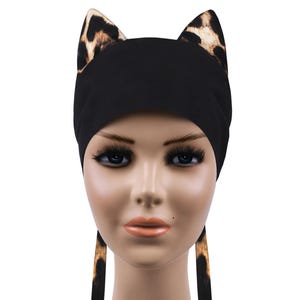 May include: Black head wrap with leopard print cat ears and matching ties. The cat ears are brown and tan. The head wrap is made of a soft material and is designed to be comfortable to wear.