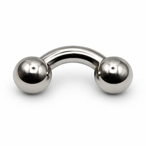Può includere: Un piercing per il corpo in stile bilanciere, di colore argento lucido. Il gioiello presenta due sfere sferiche collegate da una barra curva a forma di U. Il metallo ha una superficie riflettente e lucida.