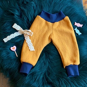 May include: Mustard yellow baby pants with navy blue elastic waistband and cuffs. The pants are made of a soft, fuzzy fabric.