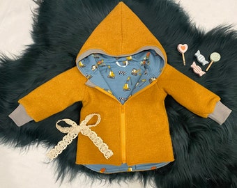 May include: A mustard yellow hooded jacket with a zipper closure and grey cuffs. The jacket has a blue lining with a pattern of yellow construction vehicles.