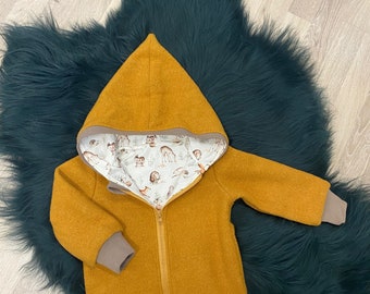 May include: A mustard yellow hooded jacket with a zipper closure and brown ribbed cuffs. The jacket is lined with a white fabric featuring a woodland animal print.