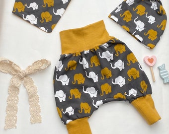 Könnte beinhalten: Ein Baby-Outfit-Set mit einem grauen und weißen Elefantenmuster. Das Set beinhaltet eine graue und senfgelbe Haremshosen, eine graue und weiße Elefantenmuster-Mütze mit einem senfgelben Band und eine graue und weiße Elefantenmuster-Lätzchen.