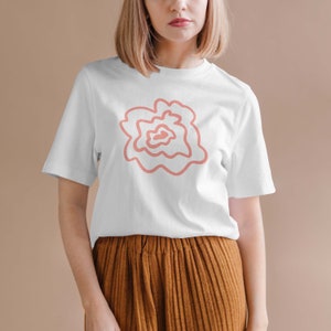 May include: A white t-shirt with a pink abstract floral design.