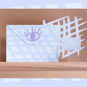 May include: A white envelope with a purple eye design on the front. The envelope is on a light brown surface with a white grid pattern in the background.