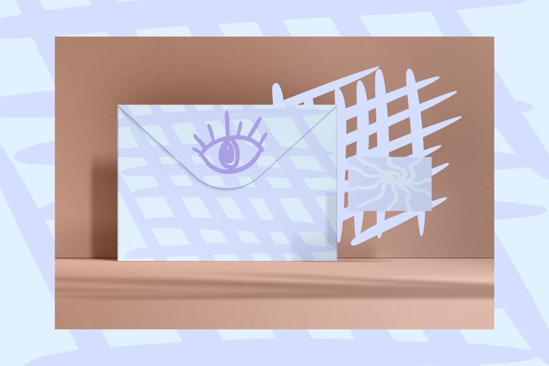 May include: A white envelope with a purple eye design on the front. The envelope is on a light brown surface with a white grid pattern in the background.