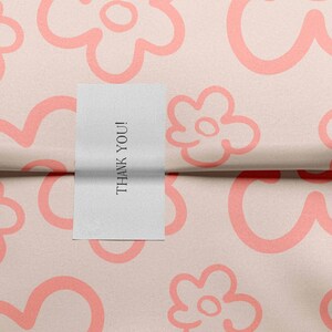 May include: A white card with the text "THANK YOU!" on it, placed on a pink background with a repeating pattern of pink flowers.