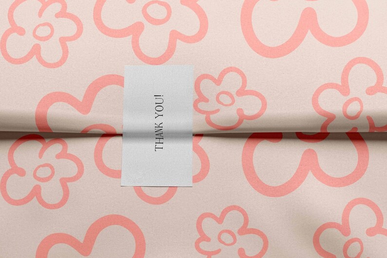 May include: A white card with the text "THANK YOU!" on it, placed on a pink background with a repeating pattern of pink flowers.