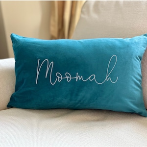 May include: Teal velvet cushion with the word "Moomah" embroidered in white.