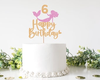 May include: Gold glitter cake topper with a pink glitter mermaid and the text "Happy Birthday" with the number 6.