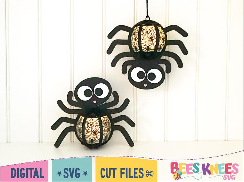 May include: Two black spider-shaped Halloween decorations with a web design on the body. The spiders are hanging from the ceiling.