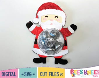 May include: A Santa Claus-shaped candy holder filled with Hershey's Kisses. The Santa figure is red with white trim and a smiling face. The candy is visible through a clear, round container.