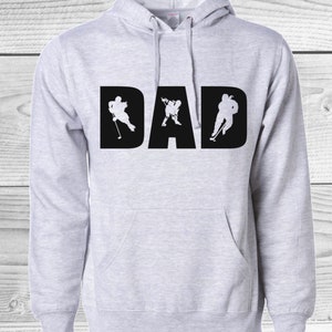 May include: Light gray hoodie with the word "DAD" in large black letters. The letters are filled with white silhouettes of hockey players in action. Features a hood and a front pocket.