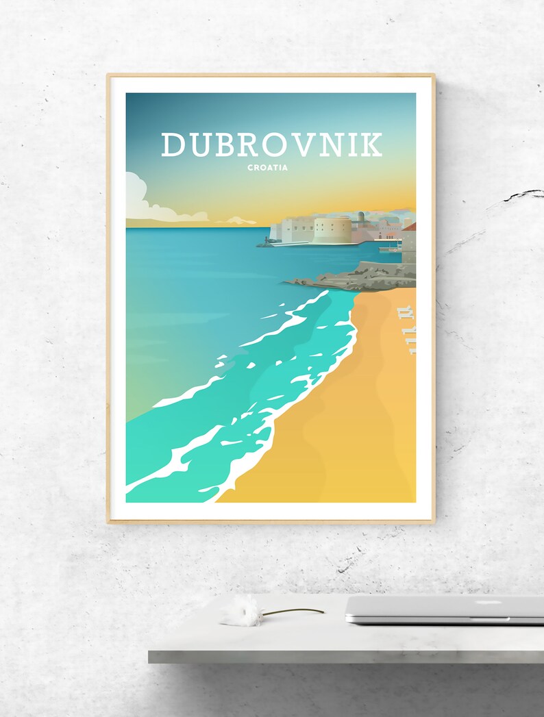 May include: A framed travel poster of Dubrovnik, Croatia, featuring a beach with turquoise water and a sandy shore. The poster has a minimalist design with the city name in white and a light blue and yellow sky.