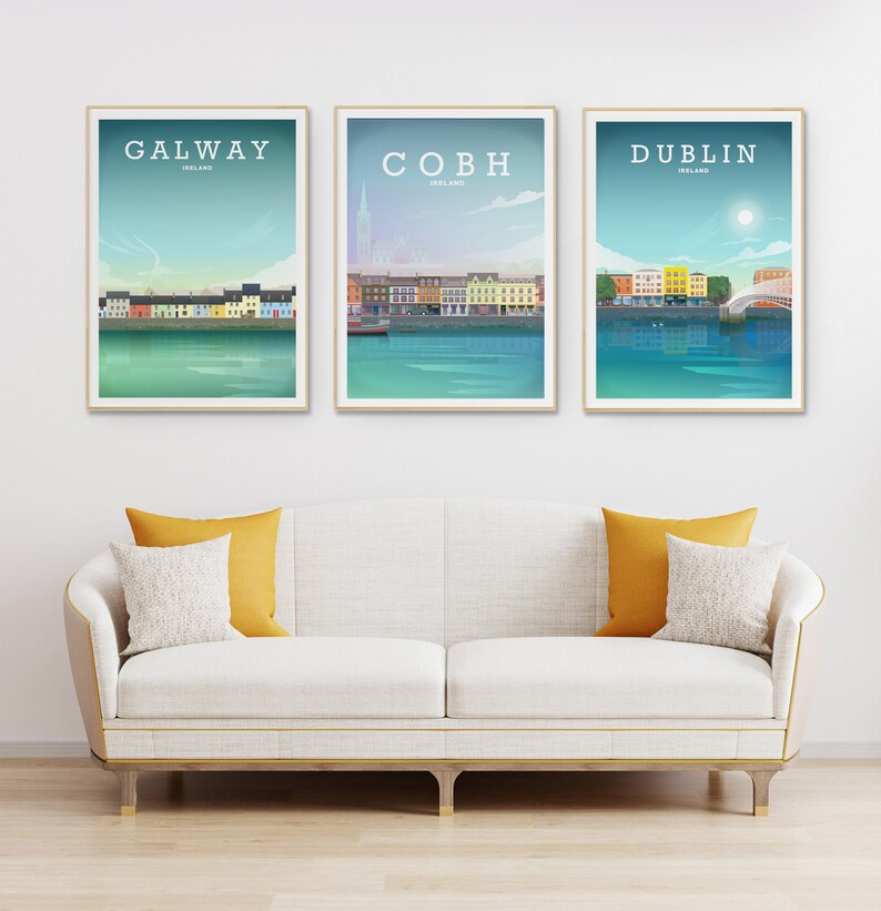 May include: Three framed travel posters featuring the cities of Galway, Cobh, and Dublin, Ireland. Each poster has a minimalist design with the city name and a depiction of the waterfront. The posters are displayed above a white sofa with yellow and white pillows.