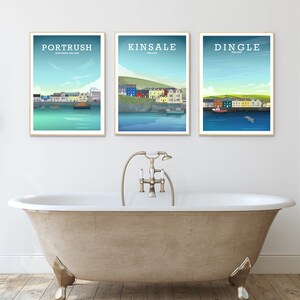 May include: Three framed prints of coastal towns in Ireland. The prints feature illustrations of the towns of Portrush, Kinsale, and Dingle. Each print has a blue background with a white border.