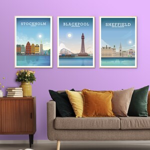 May include: Three framed city skyline posters with a light blue background and white text. The posters are hanging on a light purple wall. The posters feature the cities of Stockholm, Sweden, Blackpool, United Kingdom, and Sheffield, United Kingdom.