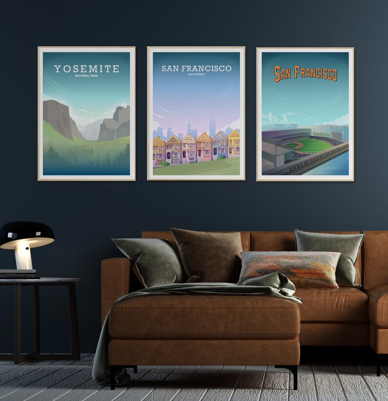Pu&ograve; includere: Tre poster incorniciati su una parete blu scuro sopra un divano in pelle marrone. I poster mostrano illustrazioni del Parco Nazionale di Yosemite, delle Painted Ladies di San Francisco e di uno stadio di baseball a San Francisco.