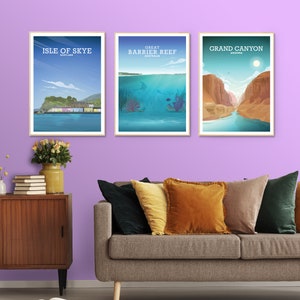 May include: Three framed travel posters on a purple wall above a gray couch with pillows. The posters feature illustrations of the Isle of Skye, the Great Barrier Reef, and the Grand Canyon.