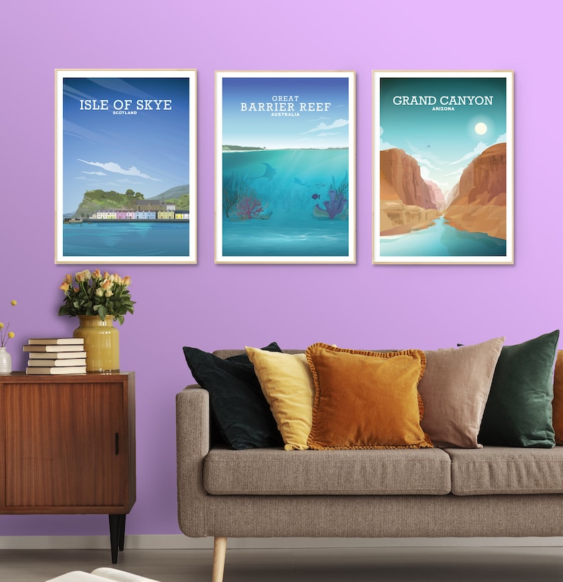 May include: Three framed travel posters on a purple wall above a gray couch with pillows. The posters feature illustrations of the Isle of Skye, the Great Barrier Reef, and the Grand Canyon.