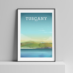May include: A framed print with a landscape scene of rolling green hills, a blue lake, and a few trees. The text "Tuscany, Italy" is printed at the top of the print.