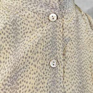 Op de afbeelding: Een beige overhemd met knopen en een bruine dierenprint. Het overhemd heeft een mandarijnkraag en een enkele knoopsluiting aan de hals.