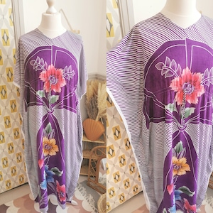 May include: A purple and white striped kaftan with floral designs. The kaftan has a V-neck and a loose fit.
