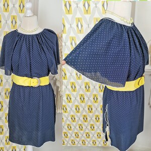 May include: A navy blue dress with white polka dots and a yellow belt. The dress has a ruffled neckline and short sleeves.
