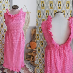 May include: A pink sleeveless dress with a ruffled neckline and hem. The dress has a floral pattern and a low back.