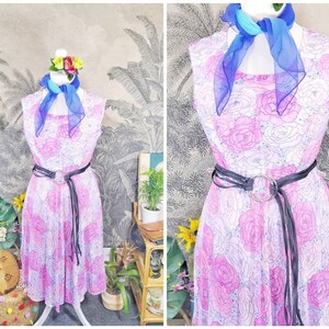 May include: A sleeveless pink and white floral dress with a black belt and a blue scarf. The dress has a fitted bodice and a full skirt.