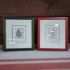 Puede incluir: Dos estampados botánicos enmarcados, uno con un marco verde y el otro con un marco rojo. El estampado en el marco verde muestra un dibujo de albahaca con el texto "Basil" y "C.C. Day" debajo del dibujo. El estampado en el marco rojo muestra un dibujo de un chile con el texto "Chili Pepper" y "C.C. Day" debajo del dibujo.
