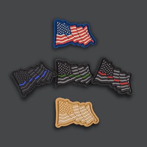 May include: A collection of flag-shaped patches in various designs. One patch features the traditional American flag, while others display black and gray flags with blue, green, and red stripes. A tan flag patch is also included.