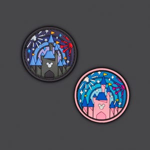 May include: Two round patches featuring a castle design with fireworks. One patch has a black border with a gray castle, blue turrets, and a white Mickey Mouse head. The other has a pink border with a pink castle and blue turrets.