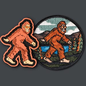 Puede incluir: Dos parches bordados con un Bigfoot de dibujos animados que lleva gafas de sol. Un parche muestra a Bigfoot caminando en un entorno de bosque con un lago, mientras que el otro parche muestra a Bigfoot caminando solo.