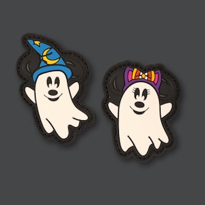 May include: Two Halloween-themed ghost patches, one with a witch hat and the other with a bow. The patches are black with white ghost outlines and colourful details.