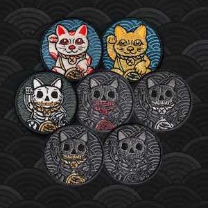May include: Seven circular embroidered patches featuring beckoning cats. Two are traditional cats in white and gold, while five are skeleton-themed cats in black and gray with various accent colors including gold, red, and white, all set against wave patterns.