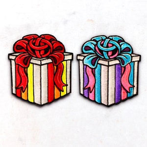 May include: Two embroidered felt gift boxes, one with red and yellow stripes and a red bow, the other with blue and purple stripes and a blue bow.