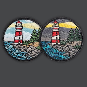 Puede incluir: Dos parches redondos bordados con una escena de faro. Los faros son rojos y blancos, sobre un fondo de agua azul, costa rocosa, árboles verdes y un cielo colorido. Los parches tienen un borde negro.