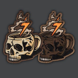 May include: Embroidered patches featuring a skull-shaped coffee mug design. The mug has a handle and is topped with steam and a lightning bolt. One patch is tan and the other is brown.