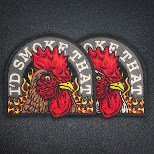 Peut inclure: Deux écussons semi-circulaires avec un motif de coq. Le coq est rouge et marron avec un bec jaune, entouré de flammes. Le texte "I'D SMOKE THAT" est arqué en haut du motif en lettres blanches.