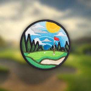 May include: Embroidered patch featuring a golf course scene. The design includes a green fairway, a white golf ball, a red flag, and a yellow sun. The patch is round with a black border and depicts a sunny day on the course.