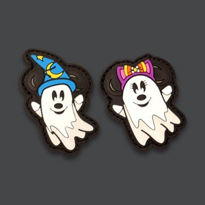 May include: Two Halloween-themed ghost patches. One is a white ghost with a blue wizard hat and the other is a white ghost with a pink bow. Both ghosts have black eyes and a black mouth.