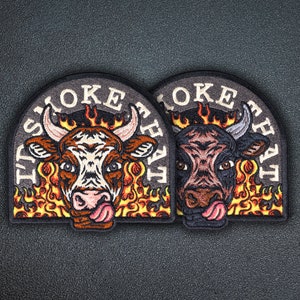 May include: Two embroidered patches with a black background and white text. The text reads "I'd Smoke That". Each patch features a bull with flames behind it. One bull is brown and white, the other is black.