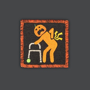 May include: Orange pumpkin-shaped character with a face and a walking stick, wearing a party hat, with a yellow lightning bolt coming out of its backside. The character is embroidered on a black fabric patch with an orange border.